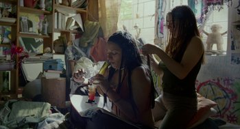 Movie still from “And Your Mother Too” (2001), directed by Alfonso Cuarón – A woman with dreadlocks is holding a drink; Medium shot, High angle