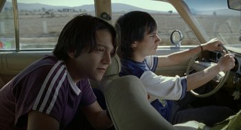 Movie still from “And Your Mother Too” (2001), directed by Alfonso Cuarón – Two young men sitting in the drivers seat of a car; Medium shot, Low angle