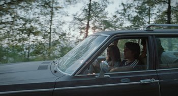 Movie still from “And Your Mother Too” (2001), directed by Alfonso Cuarón – A man and a woman in the driver's seat of a car driving down a road; Wide shot, Low angle
