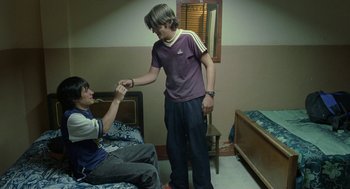 Movie still from “And Your Mother Too” (2001), directed by Alfonso Cuarón – Two young men are holding hands in a bedroom; Medium shot, High angle