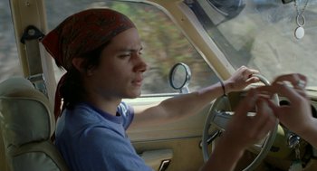 Movie still from “And Your Mother Too” (2001), directed by Alfonso Cuarón – A young man driving a car in the road; Close Up shot, Low angle