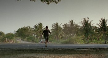 Movie still from “And Your Mother Too” (2001), directed by Alfonso Cuarón – A person running down the side of a road; Extreme Wide shot, Low angle