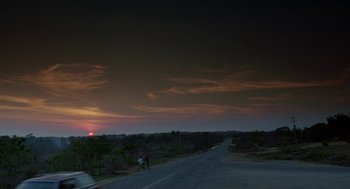 Movie still from “And Your Mother Too” (2001), directed by Alfonso Cuarón – A person riding a bike down a road at sunset; Extreme Wide shot, Low angle