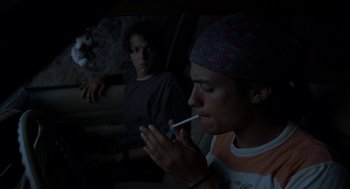 Movie still from “And Your Mother Too” (2001), directed by Alfonso Cuarón – A man smoking a cigarette while sitting next to another man in a car; Medium shot, Low angle