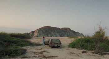 Movie still from “And Your Mother Too” (2001), directed by Alfonso Cuarón – A woman standing next to an old car in the desert; Extreme Wide shot, Low angle