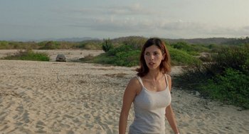 Movie still from “And Your Mother Too” (2001), directed by Alfonso Cuarón – A woman walking on the beach in a white tank top; Medium shot, Over the shoulder angle