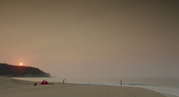 Movie still from “And Your Mother Too” (2001), directed by Alfonso Cuarón – Two people standing on the beach near a red tent; Extreme Wide shot, Low angle