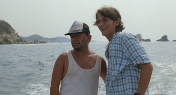 Movie still from “And Your Mother Too” (2001), directed by Alfonso Cuarón – Two men standing next to a body of water; Medium shot, Low angle