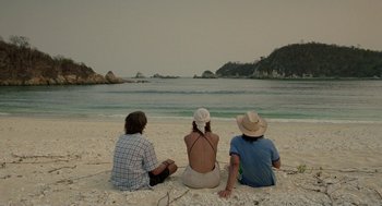Movie still from “And Your Mother Too” (2001), directed by Alfonso Cuarón – A group of people sitting on the beach looking out at the ocean; Wide shot, High angle