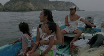 Movie still from “And Your Mother Too” (2001), directed by Alfonso Cuarón – A woman holding a child while sitting on the back of a boat in the ocean; Medium shot, High angle