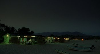 Movie still from “And Your Mother Too” (2001), directed by Alfonso Cuarón – A group of people sitting on a beach at night; Extreme Wide shot, High angle