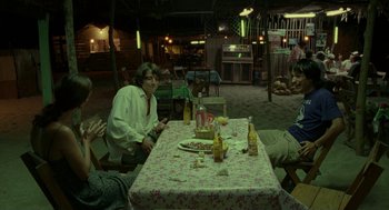 Movie still from “And Your Mother Too” (2001), directed by Alfonso Cuarón – A group of people sitting at a table with food on top of it; Wide shot, High angle