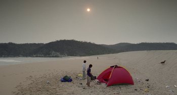 Movie still from “And Your Mother Too” (2001), directed by Alfonso Cuarón – Two people standing on a beach near a tent; Extreme Wide shot, High angle