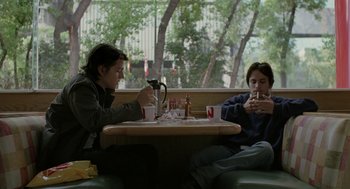 Movie still from “And Your Mother Too” (2001), directed by Alfonso Cuarón – Two people sitting at a table in a restaurant; Medium shot, Low angle