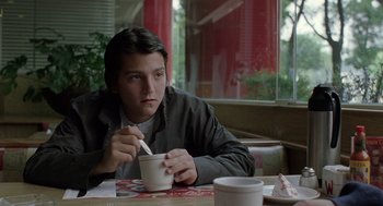 Movie still from “And Your Mother Too” (2001), directed by Alfonso Cuarón – A man sitting at a table with a bowl of food; Medium shot, Low angle