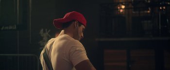 Movie still from “Angel of Anywhere” (2018), directed by James Kicklighter – A man wearing a red hat and headphones; Close Up shot, Over the shoulder angle