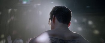 Movie still from “Angel of Anywhere” (2018), directed by James Kicklighter – A man with a tattoo on his back; Close Up shot, Over the shoulder angle
