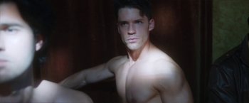 Movie still from “Angel of Anywhere” (2018), directed by James Kicklighter – A man with no shirt is sitting in a dark room; Close Up shot, High angle