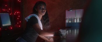 Movie still from “Angel of Anywhere” (2018), directed by James Kicklighter – A woman sitting at a table with a glass of water; Medium shot, Over the shoulder angle