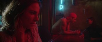 Movie still from “Angel of Anywhere” (2018), directed by James Kicklighter – A man and a woman sitting in front of a neon sign; Medium shot, Over the shoulder angle