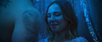 Movie still from “Angel of Anywhere” (2018), directed by James Kicklighter – A person smiling at a party; Close Up shot, Over the shoulder angle