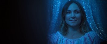 Movie still from “Angel of Anywhere” (2018), directed by James Kicklighter – A woman in a white shirt is in front of a blue curtain; Close Up shot, Low angle