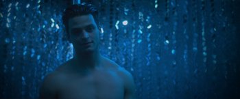 Movie still from “Angel of Anywhere” (2018), directed by James Kicklighter – A man in a blue shower curtain with lights in the background; Close Up shot, Low angle