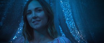 Movie still from “Angel of Anywhere” (2018), directed by James Kicklighter – A beautiful woman smiling in a blue room; Close Up shot, Low angle