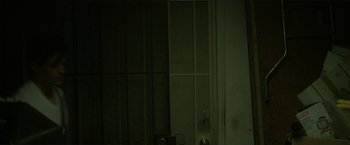 Movie still from “Angel of Anywhere” (2018), directed by James Kicklighter – A dark room with a door and a window; Medium shot, Low angle