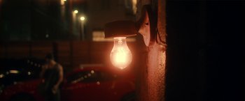 Movie still from “Angel of Anywhere” (2018), directed by James Kicklighter – A light that is hanging on the side of a building; Extreme Close Up shot, Low angle