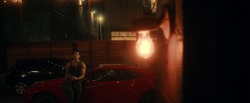 Movie still from “Angel of Anywhere” (2018), directed by James Kicklighter – A man standing in front of a red sports car at night; Wide shot, Over the shoulder angle
