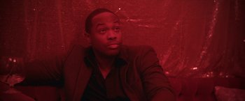 Movie still from “Angel of Anywhere” (2018), directed by James Kicklighter – A man sitting in a red room looking to his left; Close Up shot, Over the shoulder angle