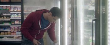 Movie still from “Angel of Anywhere” (2018), directed by James Kicklighter – A man in a red jacket is looking in a freezer; Medium shot, Low angle