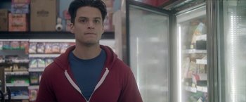 Movie still from “Angel of Anywhere” (2018), directed by James Kicklighter – A young man in a red jacket standing in front of a window; Close Up shot, Over the shoulder angle