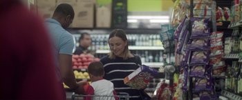 Movie still from “Angel of Anywhere” (2018), directed by James Kicklighter – A woman is holding a box of cereal while a child is holding a bag of cereal; Medium shot, Over the shoulder angle