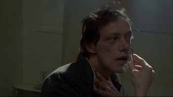Movie still from “Angst” (1983), directed by Gerald Kargl – A young man with his eyes closed is holding a cell phone to his ear; Close Up shot, Low angle
