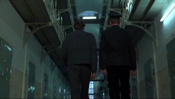 Movie still from “Angst” (1983), directed by Gerald Kargl – Two men in suits walking down a hallway; Wide shot, Low angle