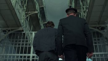 Movie still from “Angst” (1983), directed by Gerald Kargl – Two men holding hands while standing next to each other; Medium shot, Low angle