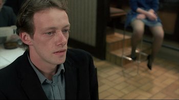 Movie still from “Angst” (1983), directed by Gerald Kargl – A man in a black jacket is sitting down; Close Up shot, Over the shoulder angle