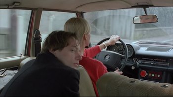 Movie still from “Angst” (1983), directed by Gerald Kargl – A man and a woman driving a car in the back of a car; Close Up shot, Over the shoulder angle