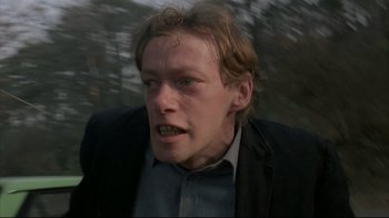 Movie still from “Angst” (1983), directed by Gerald Kargl – A person wearing a suit and tie; Close Up shot, Low angle