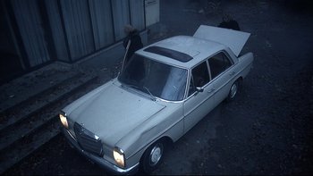 Movie still from “Angst” (1983), directed by Gerald Kargl – An old car parked on the side of the street; Wide shot, High angle