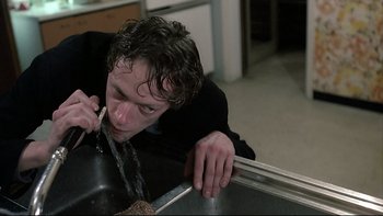 Movie still from “Angst” (1983), directed by Gerald Kargl – A man drinking water from a sink in a kitchen; Close Up shot, Low angle