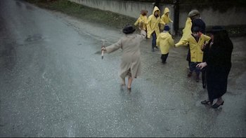 Movie still from “Angst” (1983), directed by Gerald Kargl – A group of people walking down the street in the rain; Wide shot, High angle