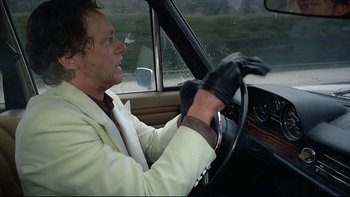 Movie still from “Angst” (1983), directed by Gerald Kargl – A man in a white jacket driving a car; Close Up shot, Low angle
