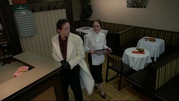 Movie still from “Angst” (1983), directed by Gerald Kargl – A man and a woman dressed in white in a restaurant setting; Medium shot, High angle