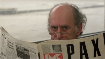 Movie still from “Angst” (1983), directed by Gerald Kargl – A man with glasses reading a newspaper; Close Up shot, Low angle