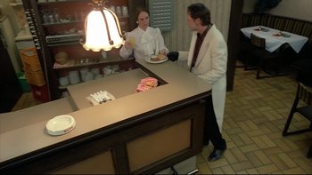 Movie still from “Angst” (1983), directed by Gerald Kargl – Two men in white jackets standing at a counter; Wide shot, High angle