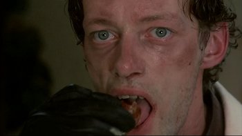 Movie still from “Angst” (1983), directed by Gerald Kargl – A person eating a piece of food; Extreme Close Up shot, Low angle