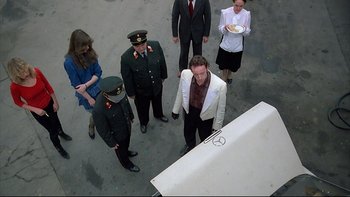 Movie still from “Angst” (1983), directed by Gerald Kargl – A group of people standing next to a table; Wide shot, High angle
